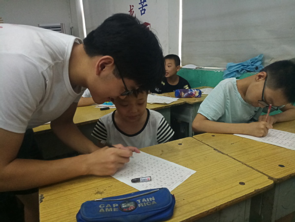 志愿者指导小孩子们写硬笔书法